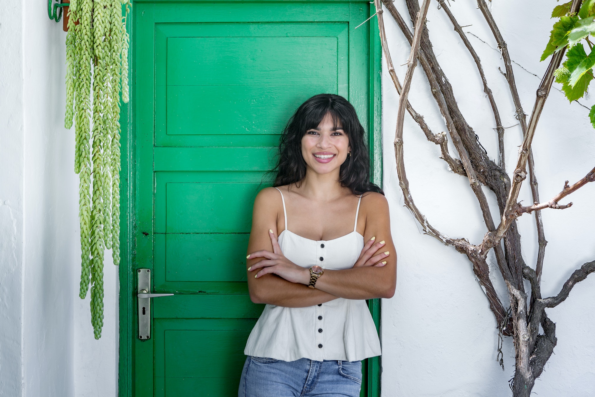 Positive Hispanic woman standing near green door